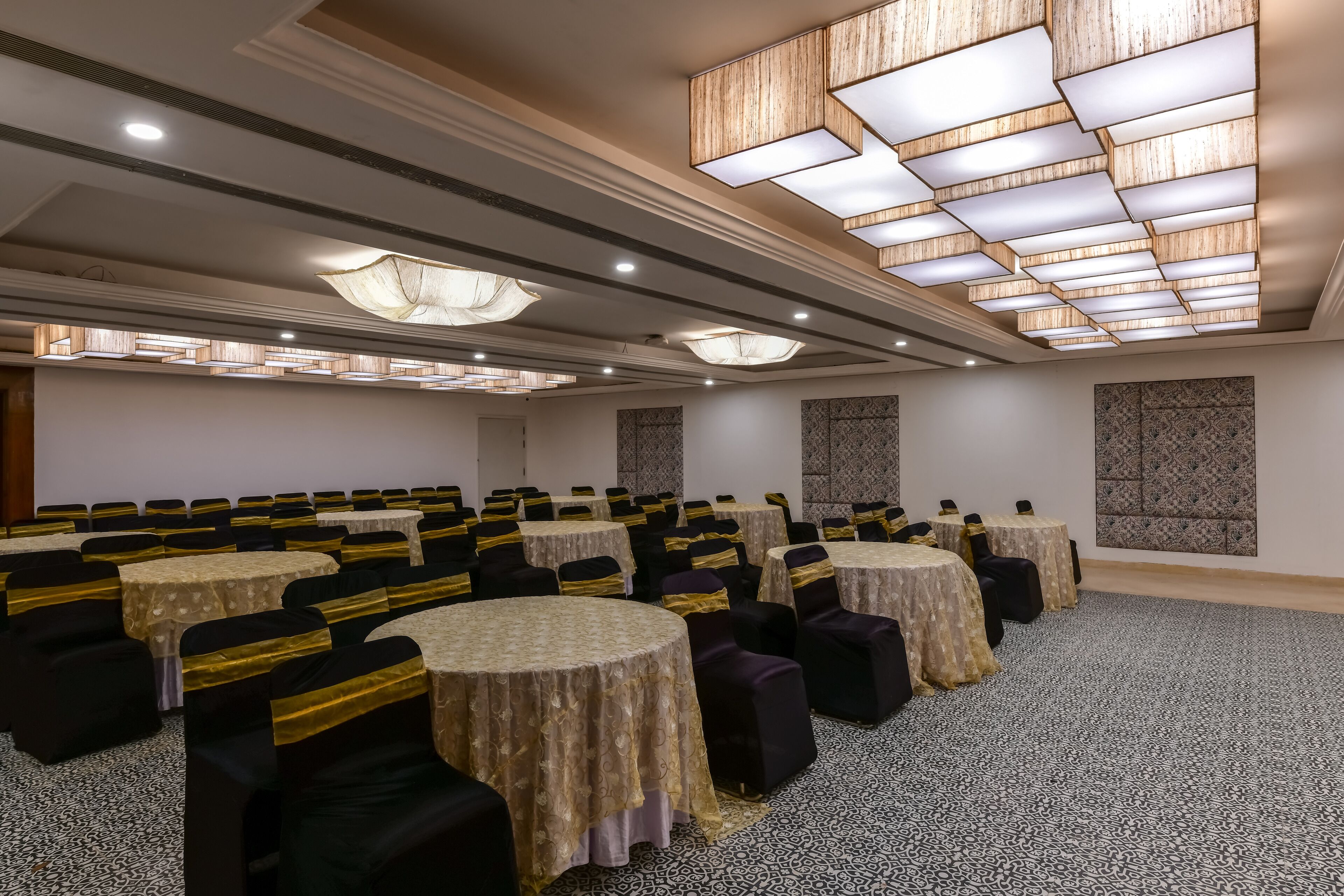A conference room with round tables, black and gold chairs, and patterned carpets.