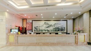 A reception area with a marble counter, a large framed painting, and a computer monitor. - Fulong Hotel (Ya'an)