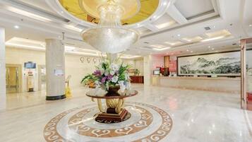 A lobby with a central decorative fountain, a reception desk, and a large mural on the wall.