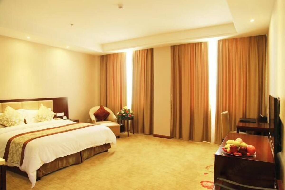 A hotel room with a bed, a desk, a chair, curtains, and a television.