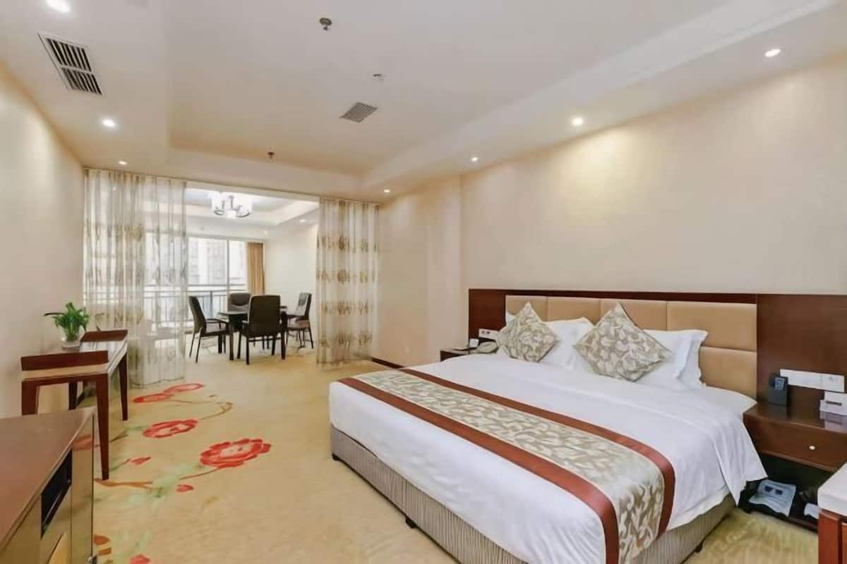 A hotel room with a large bed, a desk, and a chair.