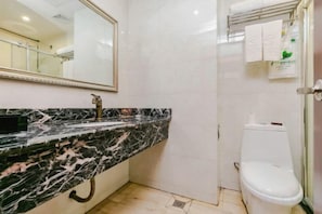 A bathroom with a marble sink, a toilet, and a mirror. - Fulong Hotel (Ya'an)