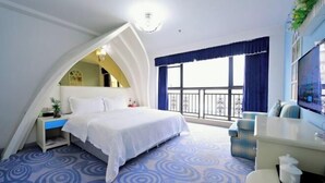 A bedroom with a bed, a small desk, a chair, a TV, and a balcony with a railing. - Fulong Hotel (Ya'an)