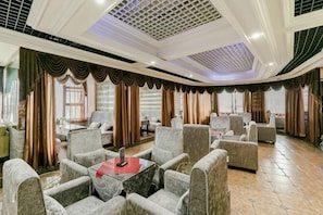 A spacious room with multiple seating areas, a central table, and a high ceiling with a grid pattern. - Fulong Hotel (Ya'an)