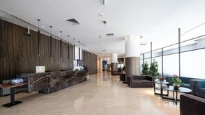 Eine großzügige Lobby mit Rezeption, Sitzgelegenheiten und großen Fenstern.