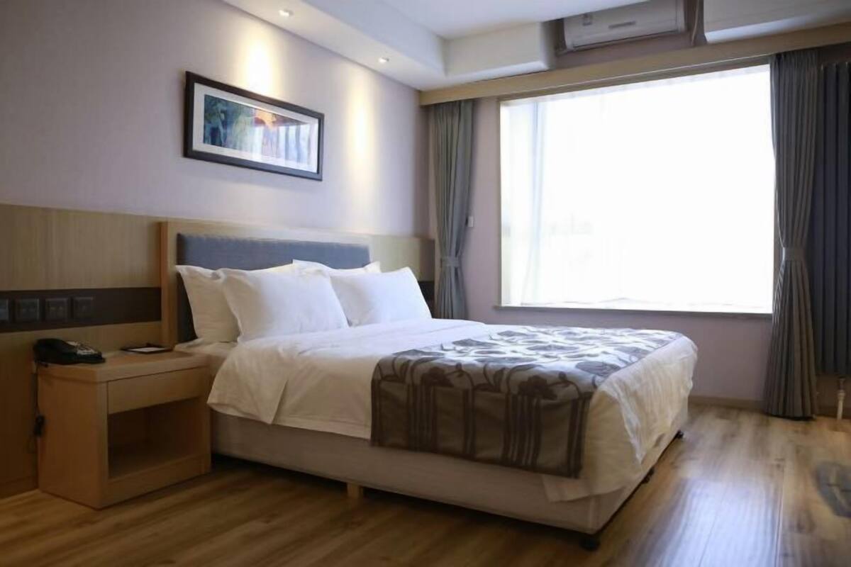 Une chambre d’hôtel avec un lit, une table de chevet et une fenêtre avec des rideaux.