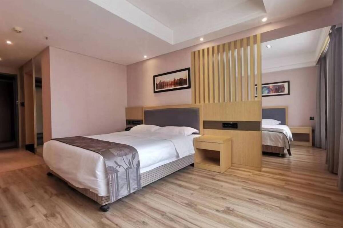 Une chambre d’hôtel moderne avec un grand lit, une table de chevet en bois, un bureau et un miroir.