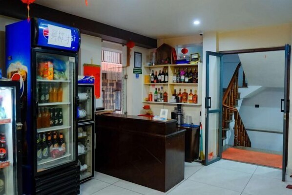 Zona de bar con refrigerador de Pepsi, estantes con licores y una barra de madera.