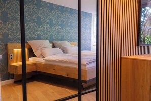 Cozy retreat with a wooden bed, nightstand, and wardrobe, set against a unique wallpaper.