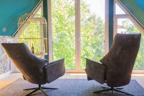 Relax in a serene space with a view of lush greenery, featuring a comfortable seating area and a unique decorative element.