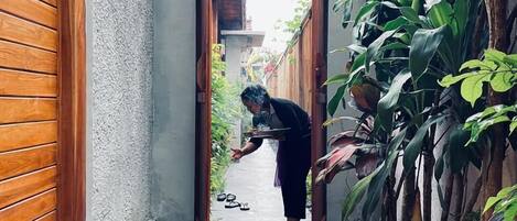 A narrow pathway leading to a doorway with a person carrying a tray.
