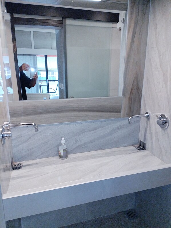 A modern bathroom with a large mirror, a marble sink, and a handheld soap dispenser. - Seafront Apartment With Sea View Yr11 (Thessaloniki)