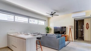 Een moderne keuken met een centraal eiland, een grijze bank en een televisie in een woonruimte.