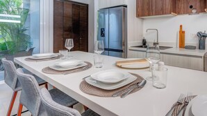 Een moderne keuken met een eethoek voor vier personen, met een koelkast, houten keukenkastjes en een groot raam.