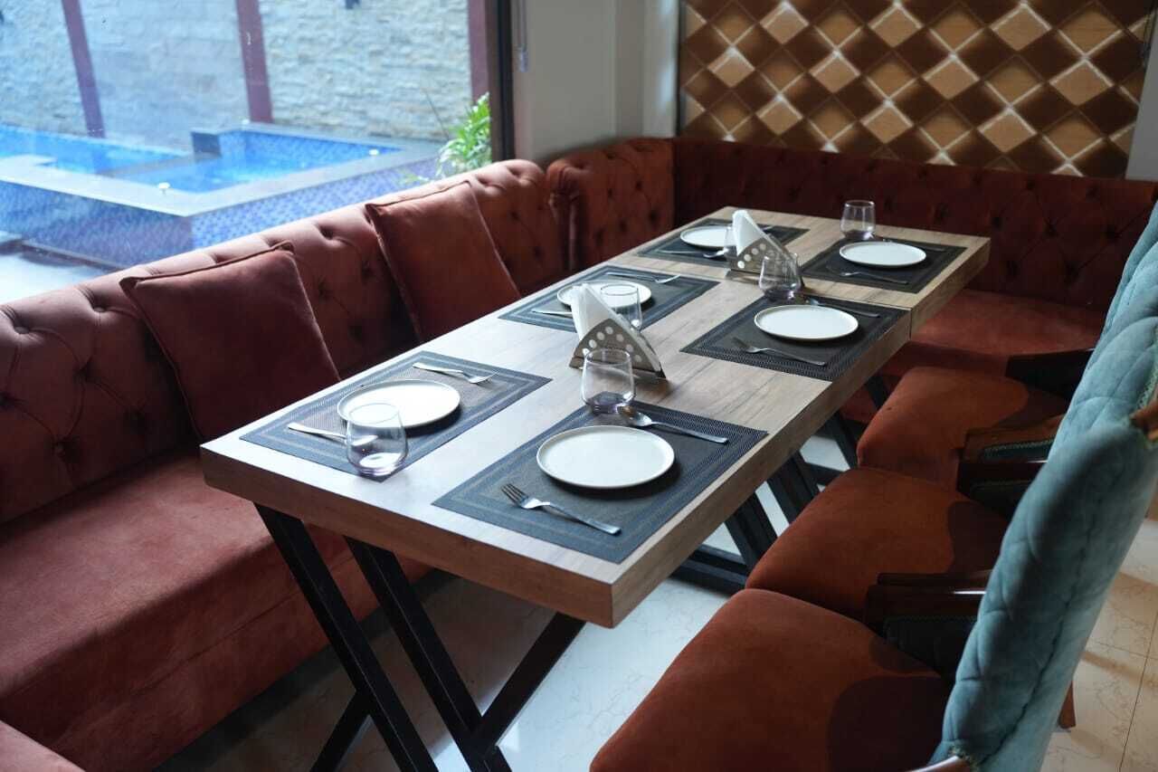 A dining area with a long table set for four, surrounded by cushioned seating.