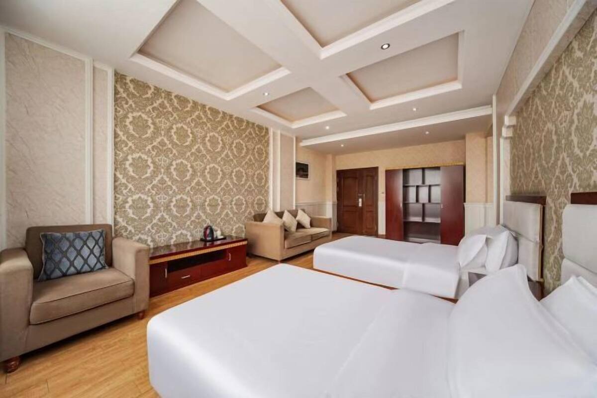 A hotel room with a large bed, a sofa, a desk, and a wardrobe.
