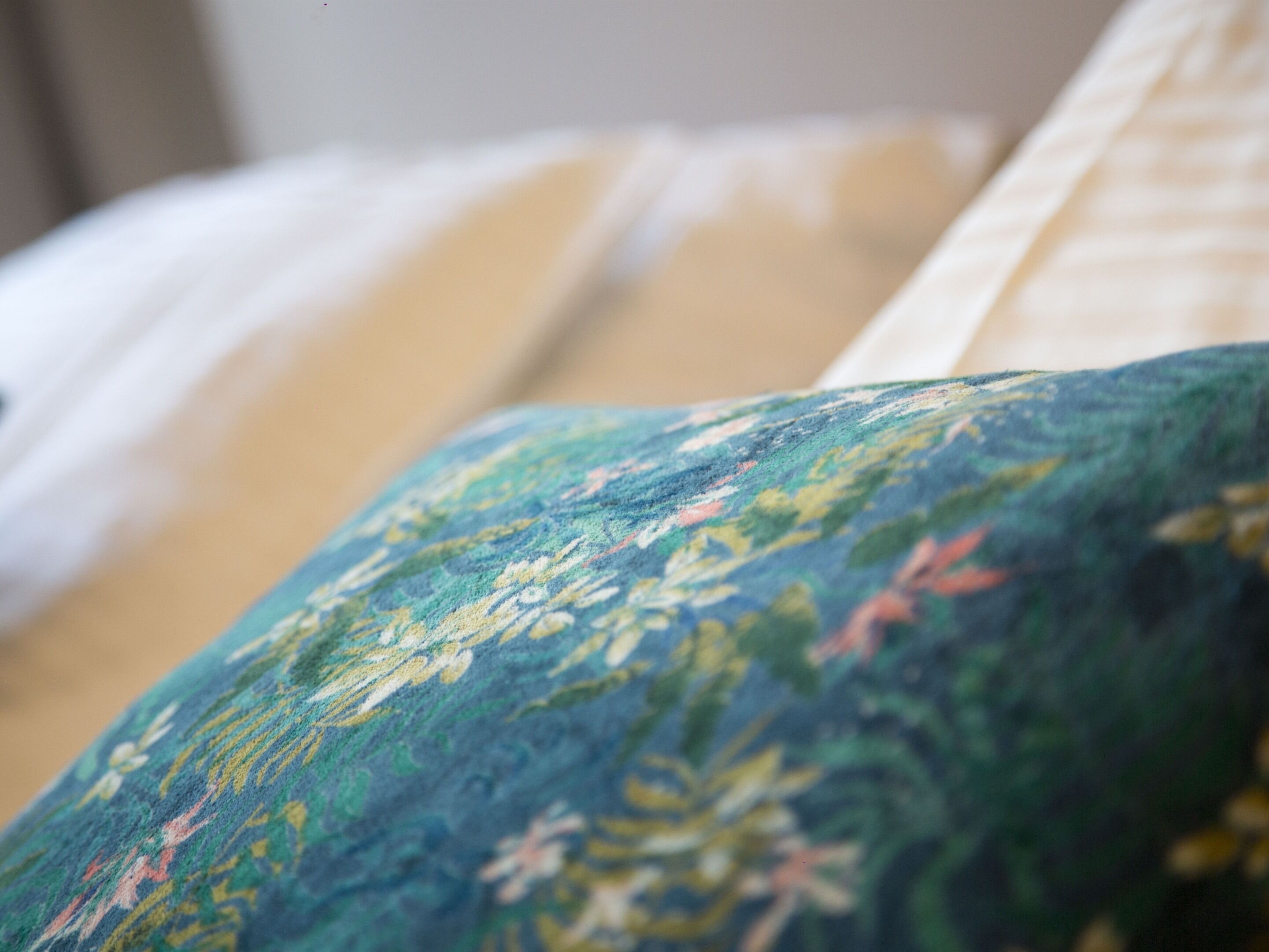 Un gros plan d’un lit avec un oreiller à motifs floraux et un oreiller blanc.