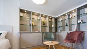 A modern room with a bed, a round table with a chair, and a shelving unit with books and decorative items. - La Chartreuse-Bordeaux (Bordeaux)