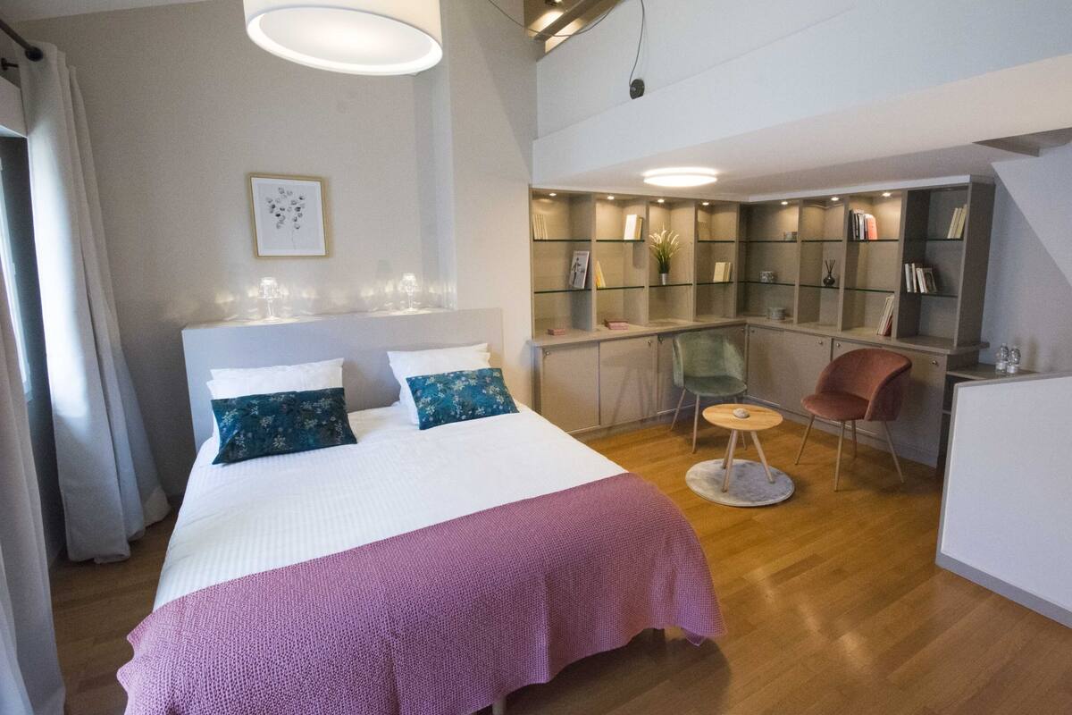 A modern bedroom with a large bed, a desk, and a chair.