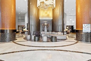A spacious lobby with a central seating area, a chandelier, and a reception desk.