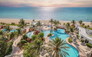Un complexe hôtelier doté de plusieurs piscines, de palmiers et offrant une vue sur la plage.