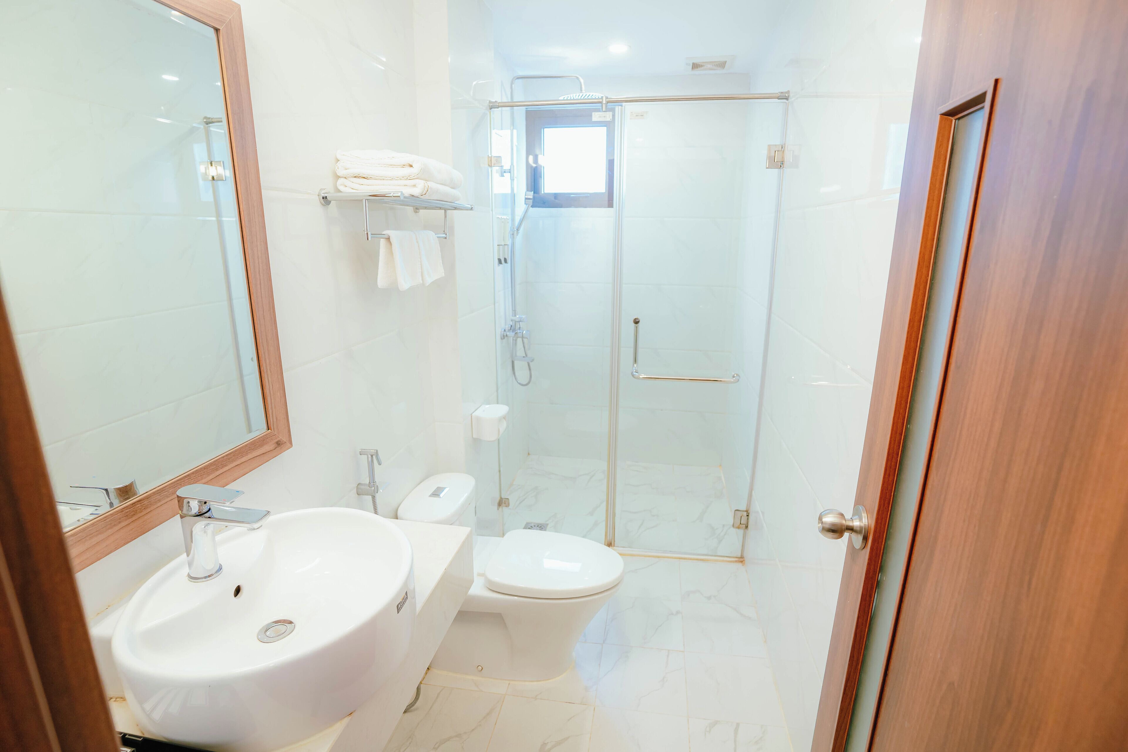 A modern bathroom with a white sink, toilet, and glass-enclosed shower.