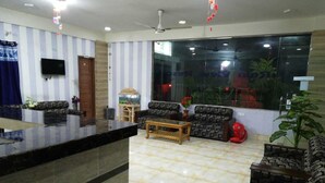 A hotel lobby with striped walls, a reception desk, sofas, a coffee table, and a large window with a view of greenery. - Resort Rain View Hotel Cox's Bazar (Cox's Bazar)