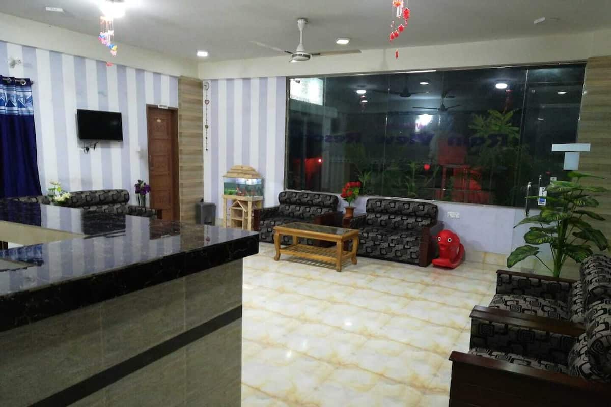 A hotel lobby with striped walls, a reception desk, sofas, a coffee table, and a large window with a view of greenery.