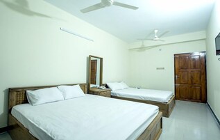 Una habitación con dos camas, un ventilador de techo, una puerta de madera y un espejo en la pared.