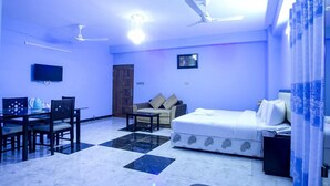 A room with a bed, a sofa, a dining table with chairs, a television, and ceiling fans. - Resort Rain View Hotel Cox's Bazar (Cox's Bazar)
