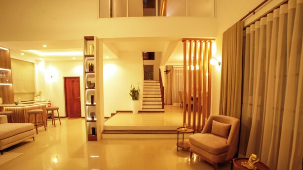 A spacious living area with a high ceiling, a staircase leading to an upper floor, and a seating area with a sofa and armchairs. - The Grand Bliss, Kottawa, 3-bedroom villa with AC, WiFi, Private Pool, and Gym (Pannipitiya, Kottawa)