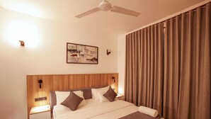 A hotel room with a large bed, wooden headboard, a ceiling fan, a painting on the wall, and a window with curtains. - The Grand Bliss, Kottawa, 3-bedroom villa with AC, WiFi, Private Pool, and Gym (Pannipitiya, Kottawa)
