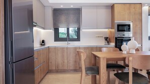 Una cocina moderna con armarios de madera, un refrigerador de acero inoxidable, una mesa de comedor con sillas y una ventana con vistas.