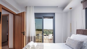 Un dormitorio moderno con una cama grande, un balcón con mesa y sillas, y vistas al paisaje.