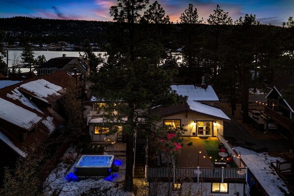 A residential property with a visible swimming pool, a covered outdoor area, and a house with a lit entrance.
