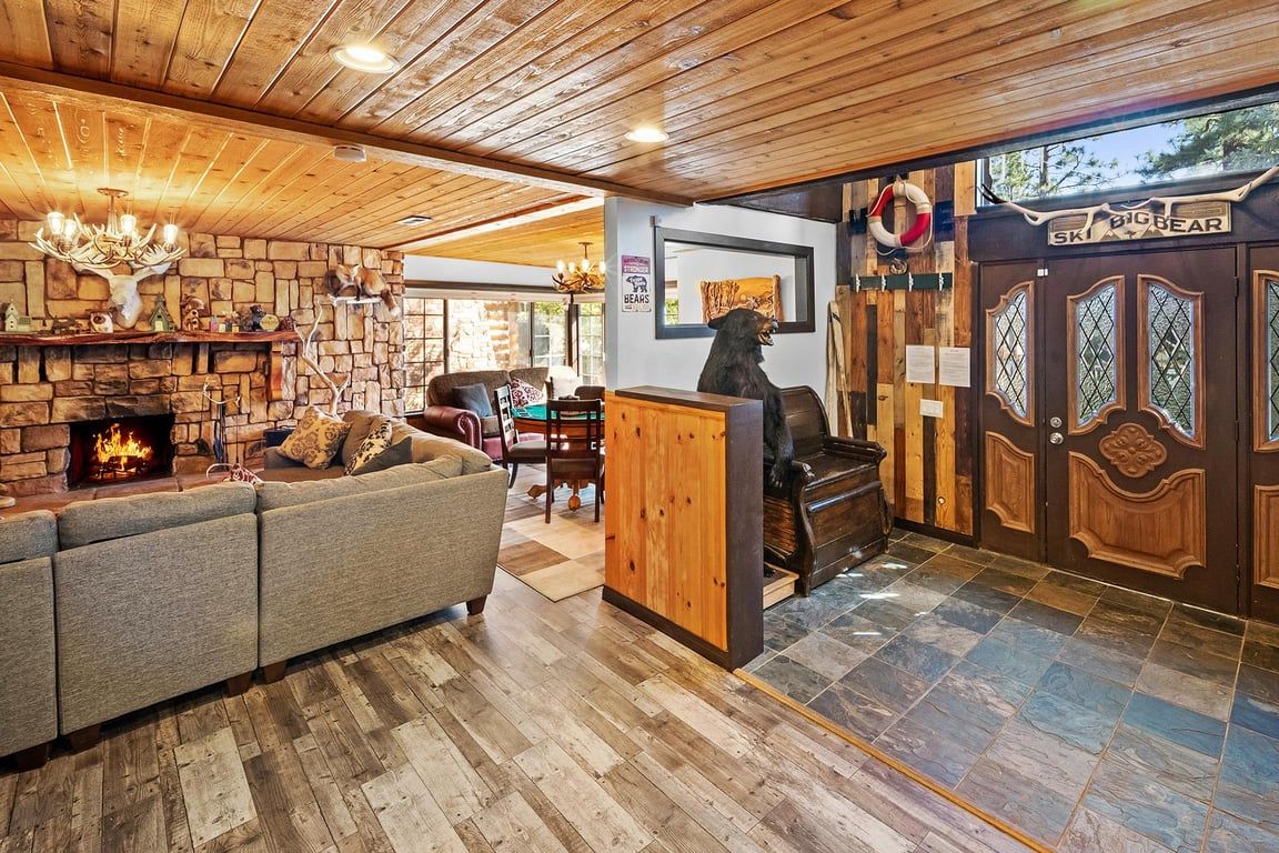 A cozy interior with a stone fireplace, a sofa, and a bear statue.