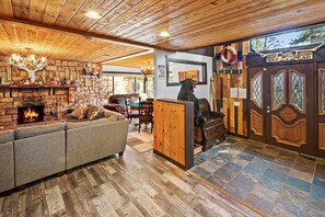 Een gezellig interieur met een stenen open haard, een bank en een beerbeeld.
