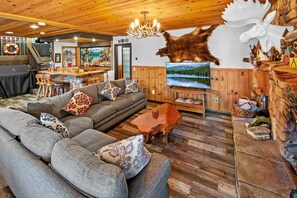 A cozy living room with a large sofa, a coffee table, and a television. - Lake Pointe Retreat By Destination Big Bear:Close to Village and Marina! Hot Tub! Pool Table! Shuffleboard! Air Hockey! Fully Fenced Yard! Pet Friendly! (Big Bear Lake)