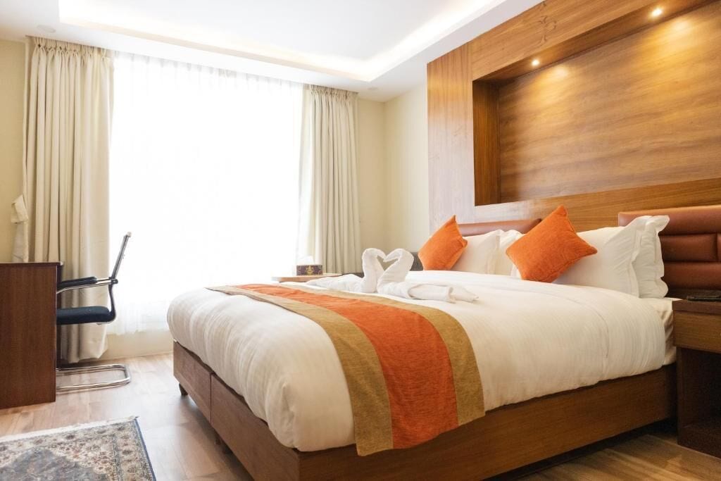 A hotel room with a large bed, wooden headboard, and a desk with a chair.