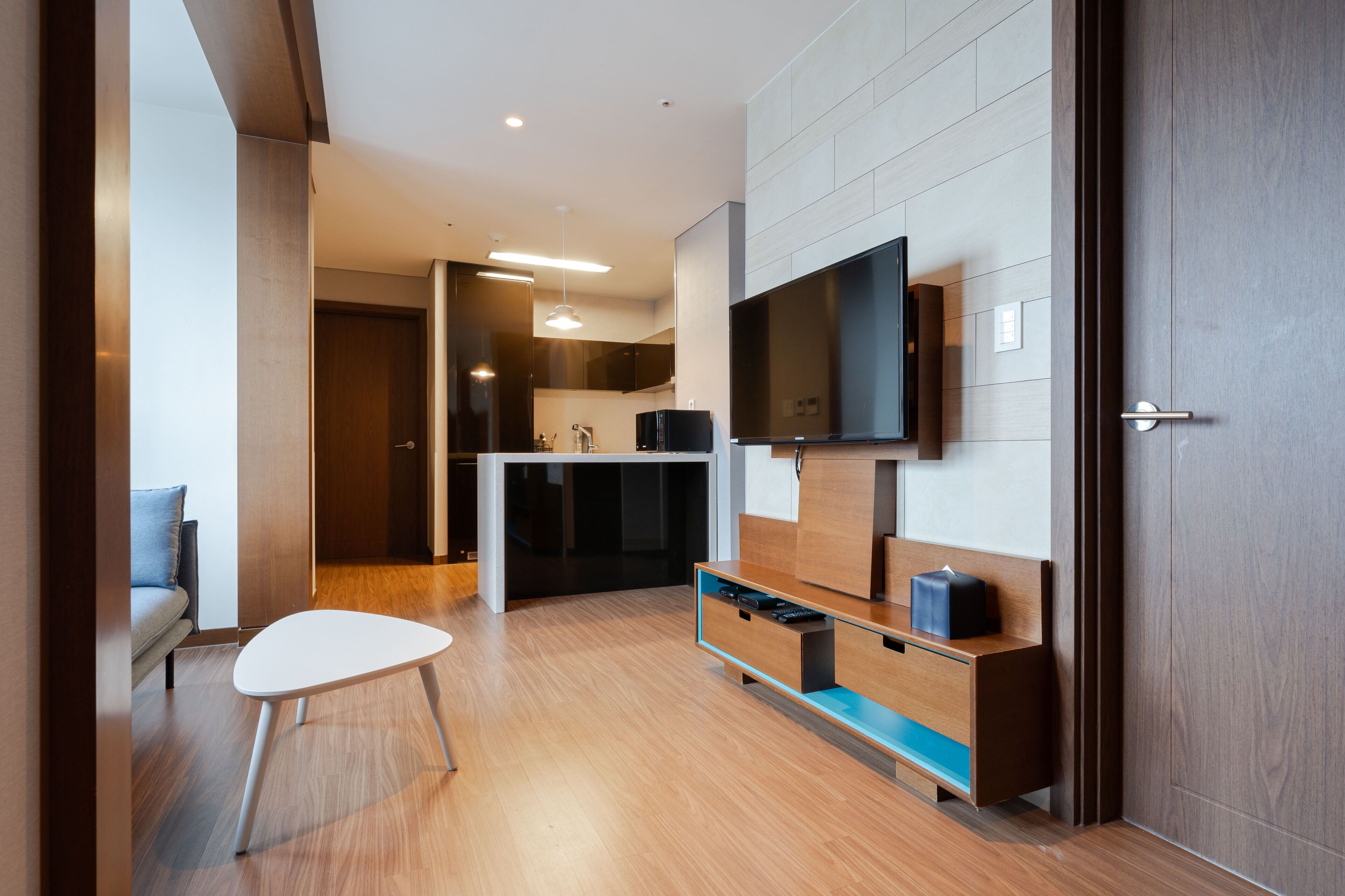 Un soggiorno moderno con una TV a schermo piatto montata a parete, un tavolino in legno e un divano.