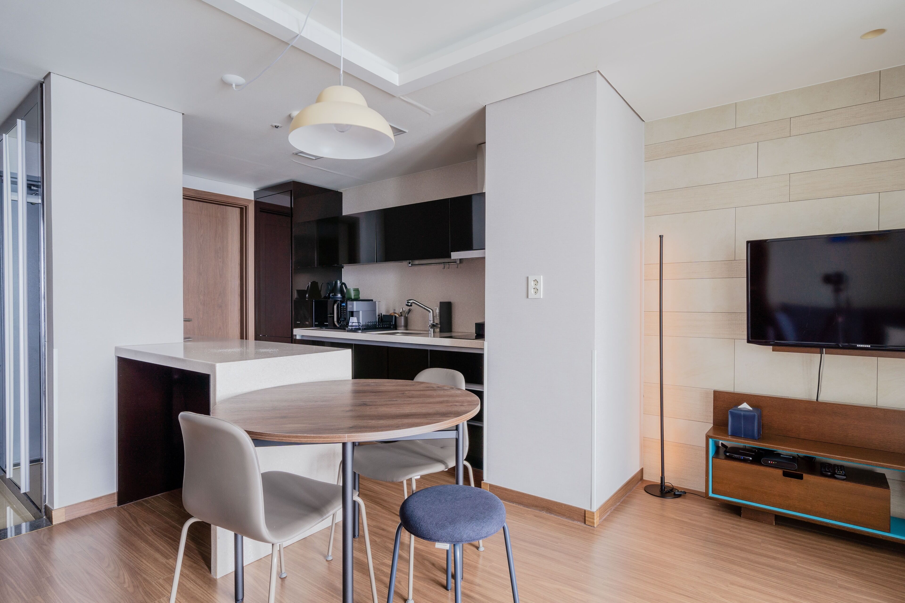 Una cocina moderna con comedor, televisor de pantalla plana y mesa de madera.