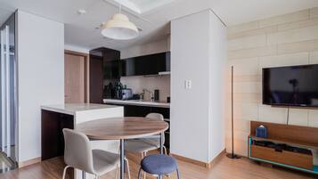 Una cocina moderna con comedor, televisor de pantalla plana y mesa de madera.