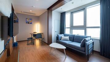 A modern living room with a sofa, a small table, and a TV mounted on the wall.