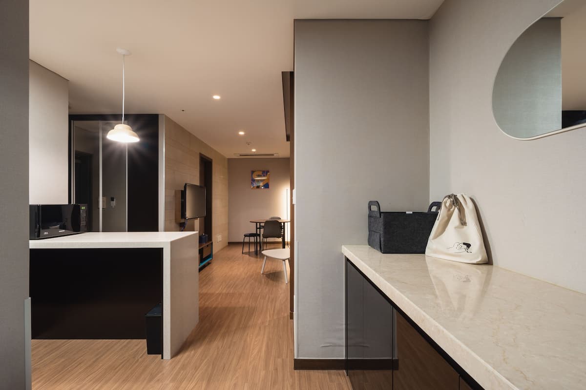 Una cocina moderna con microondas, una lámpara colgante y un bolso sobre la encimera.