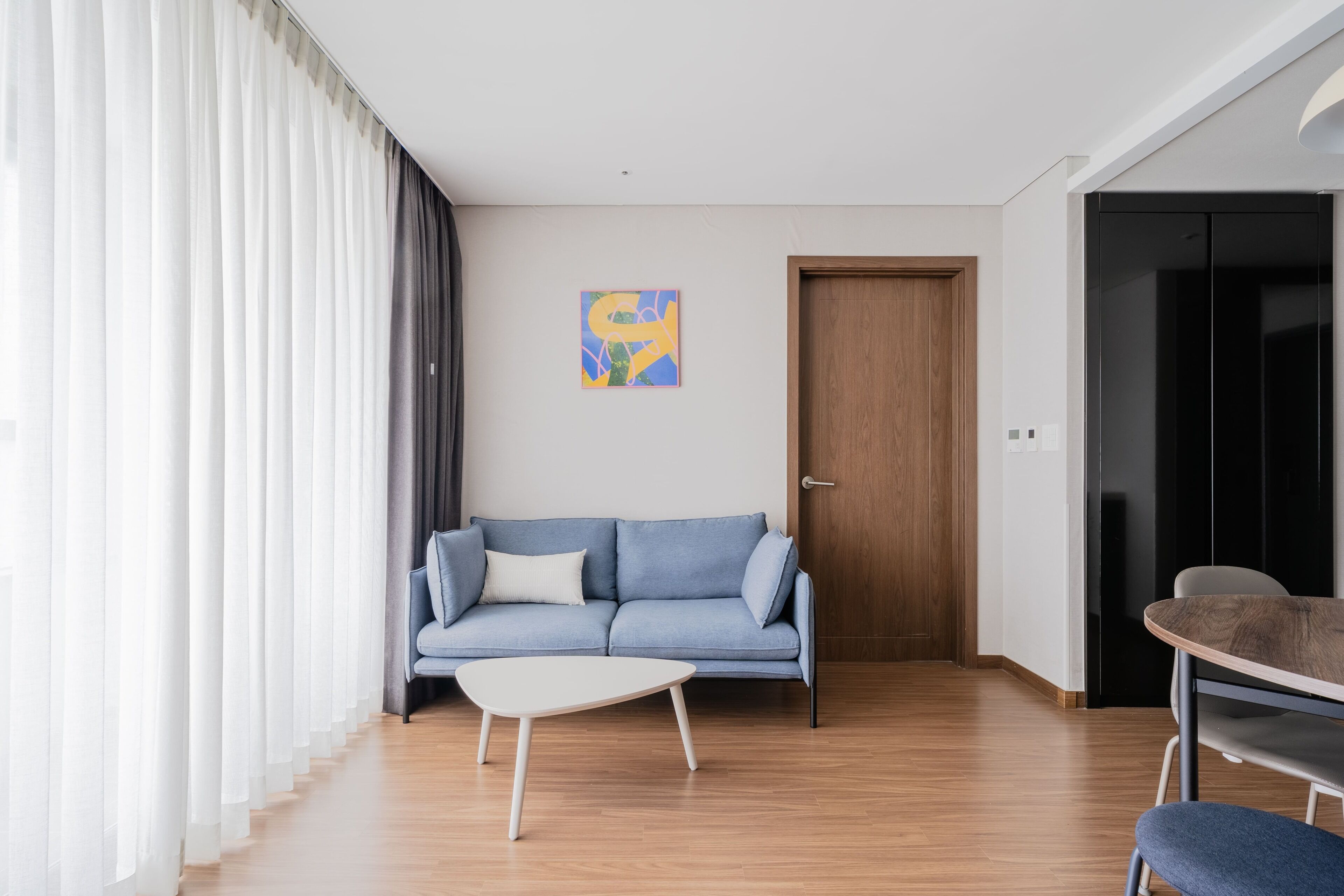 A modern living room with a blue sofa, a white coffee table, and a wooden floor.