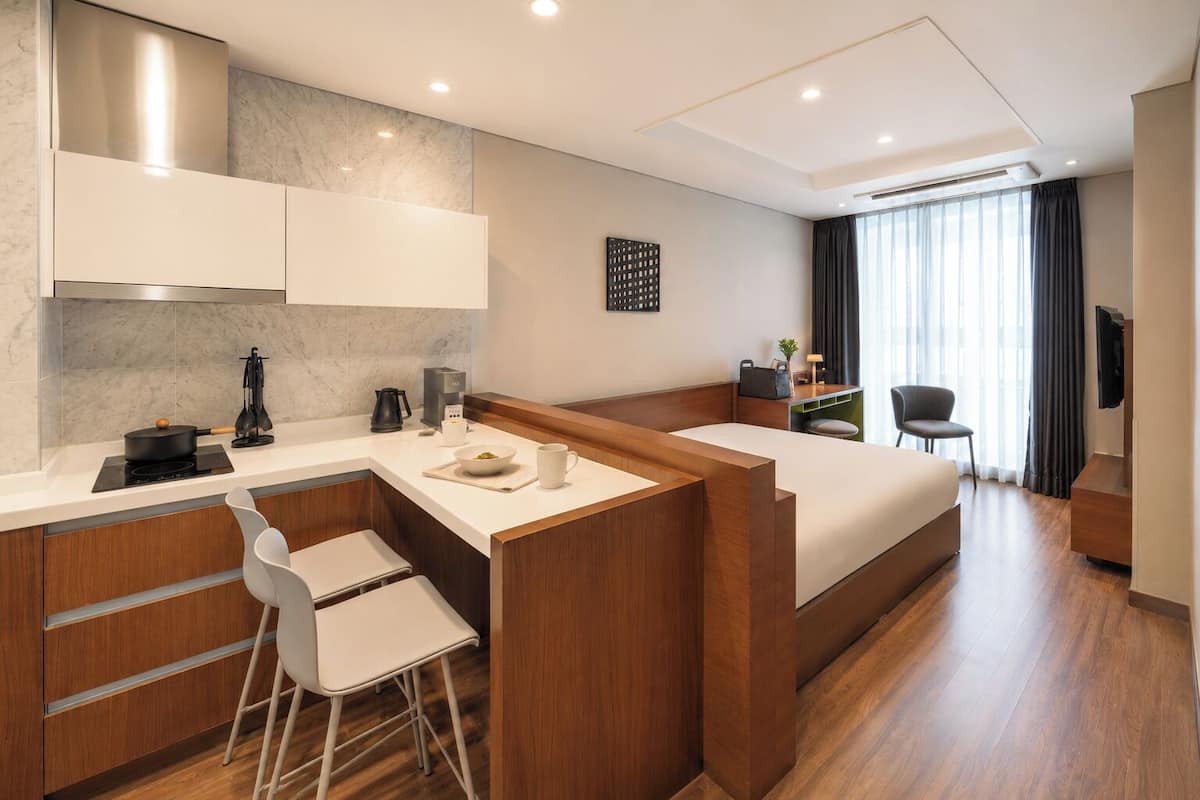 Una habitación de hotel moderna con kitchenette, una cama, un escritorio y una silla.