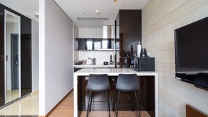 Una cocina moderna con una isla central, dos taburetes de bar y un televisor de pantalla plana montado en la pared.