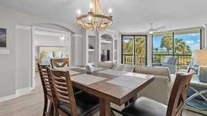 A spacious dining area with a wooden table and chairs, a chandelier, and a view of the outdoors.