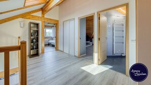 A spacious loft with high ceilings, wooden beams, and a skylight. It features a kitchen area with modern appliances and a dining space.
