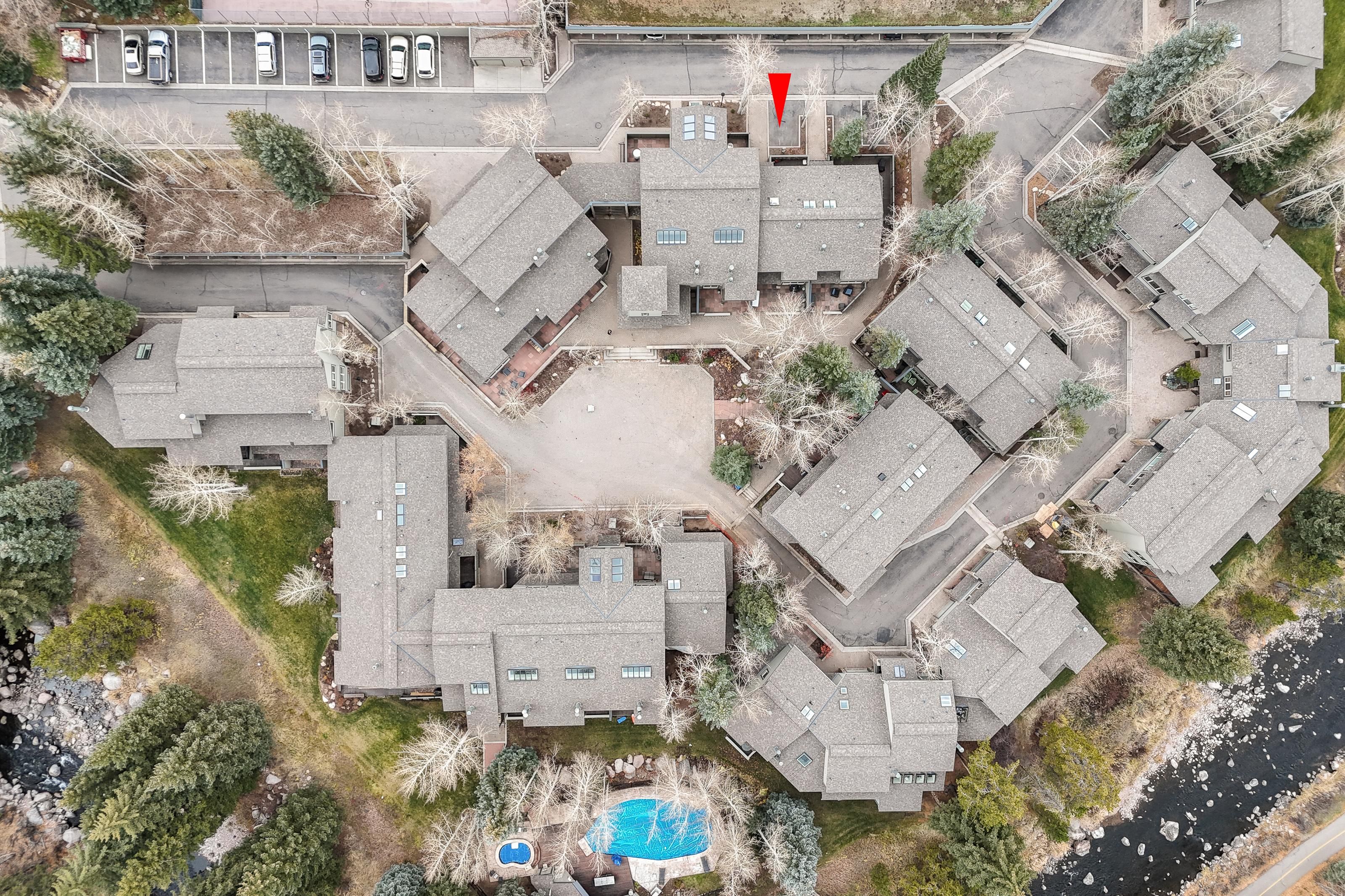 Vue aérienne d’un quartier résidentiel comprenant plusieurs maisons, une piscine et un parking.